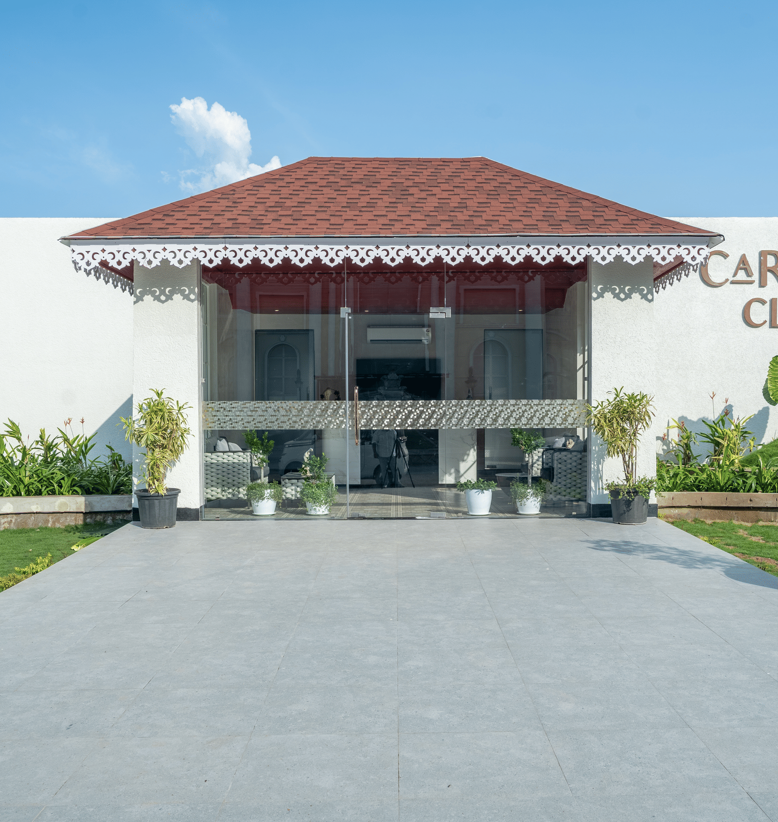 Exterior of the 'Cartier Club' building, a white structure with a red roof, fronted by a paved walkway and green lawn at Hotel Hukam's Lalit Mahal.
