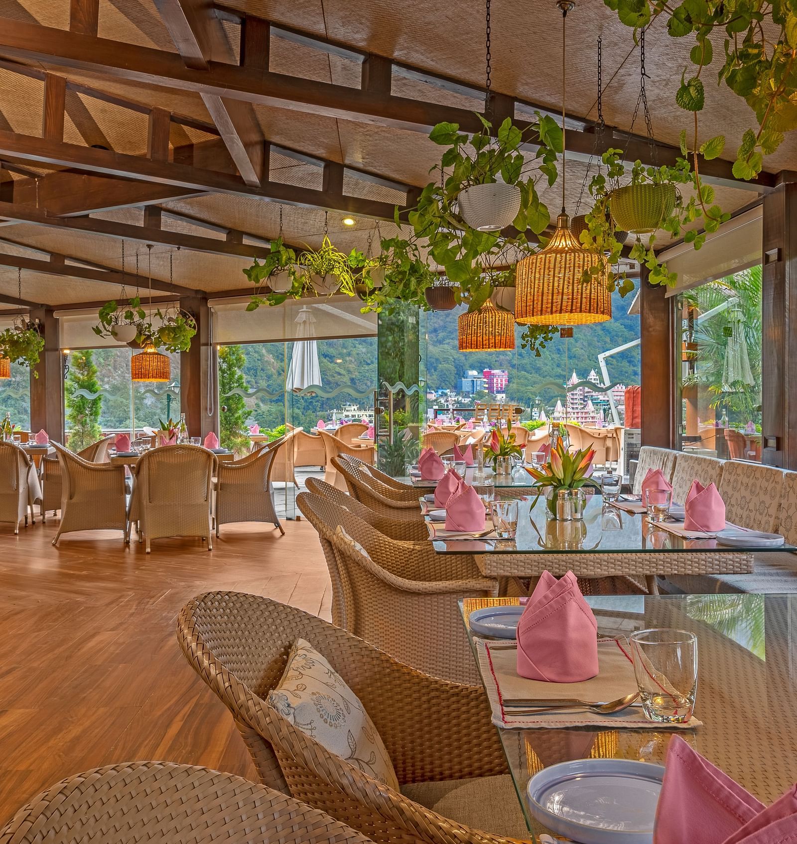 A spacious restaurant with a wooden floor and exposed wooden beams on the ceiling. Large windows offer views of the outdoors.