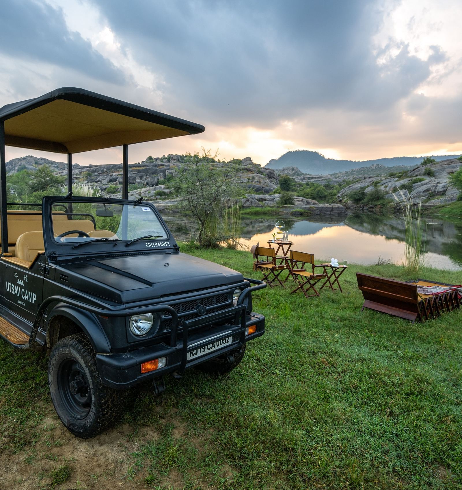 An image of a jeep parked amidst an open field with greenery - Utsav Camp Sariska