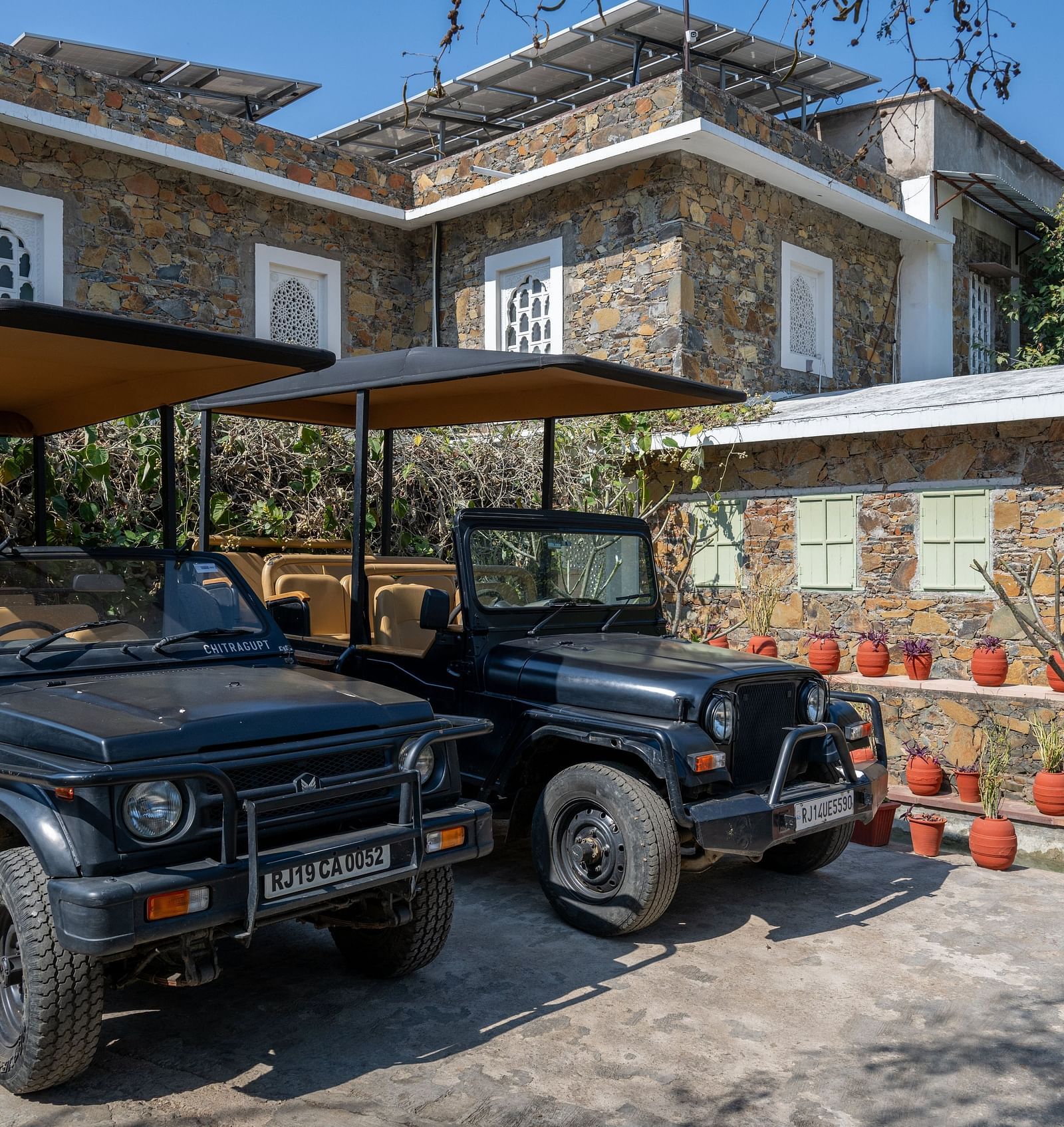 Two jeeps placed in front of a building made out of stone - Utsav Camp