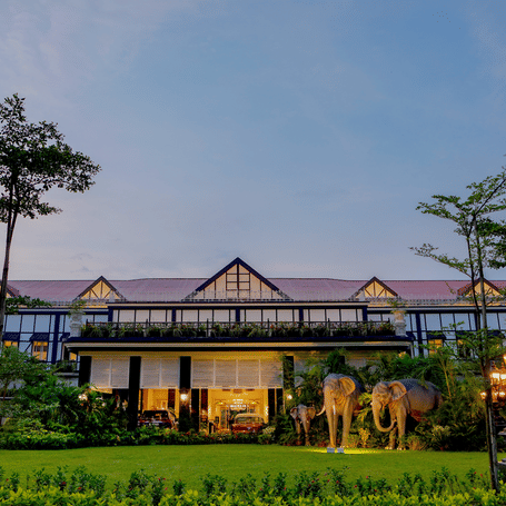 Twilight view of the elegant, long-frontage building at MAYFAIR Tea Resort Siliguri set behind a manicured lawn.