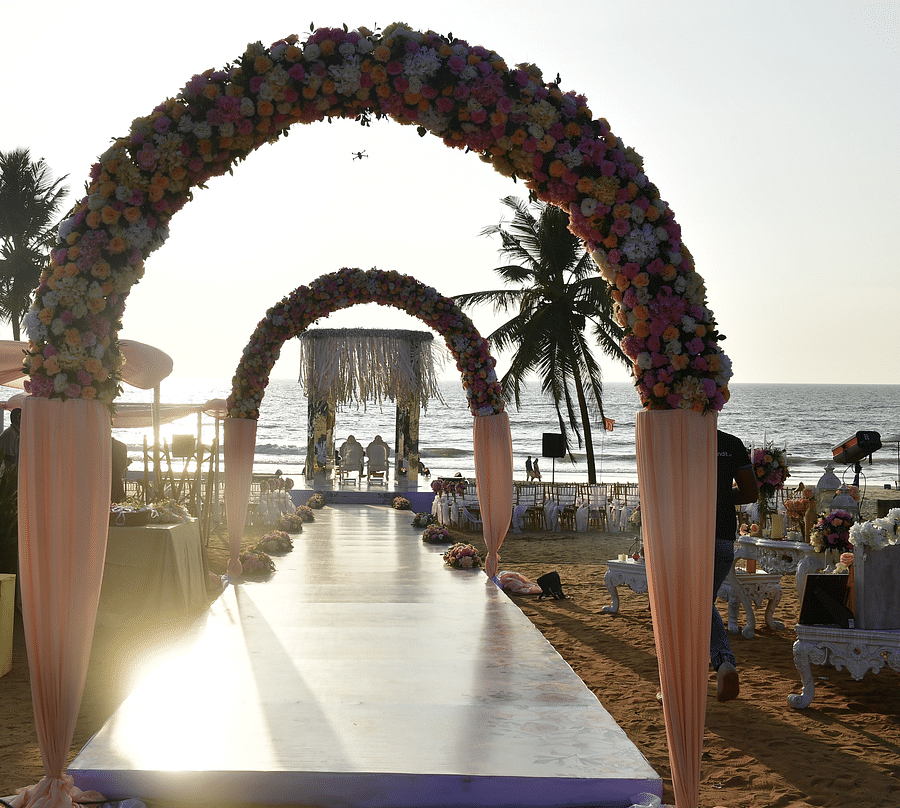 alt-text Archways leading to beach decorated with flowers for your destination wedding venue in goa