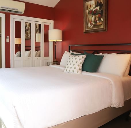 Hotel room with red walls, bed, and a lamp beside the bed at Hartstone Inn.
