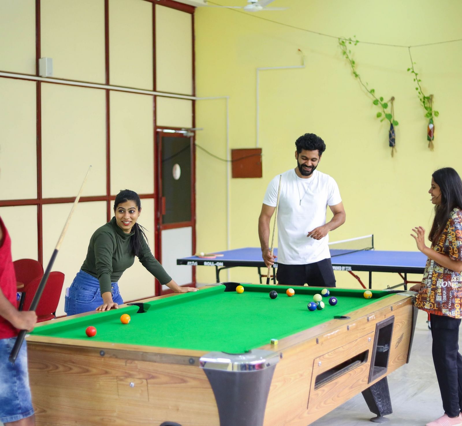 An indoor snooker table and four persons playings snooker on it at Avana Resort.