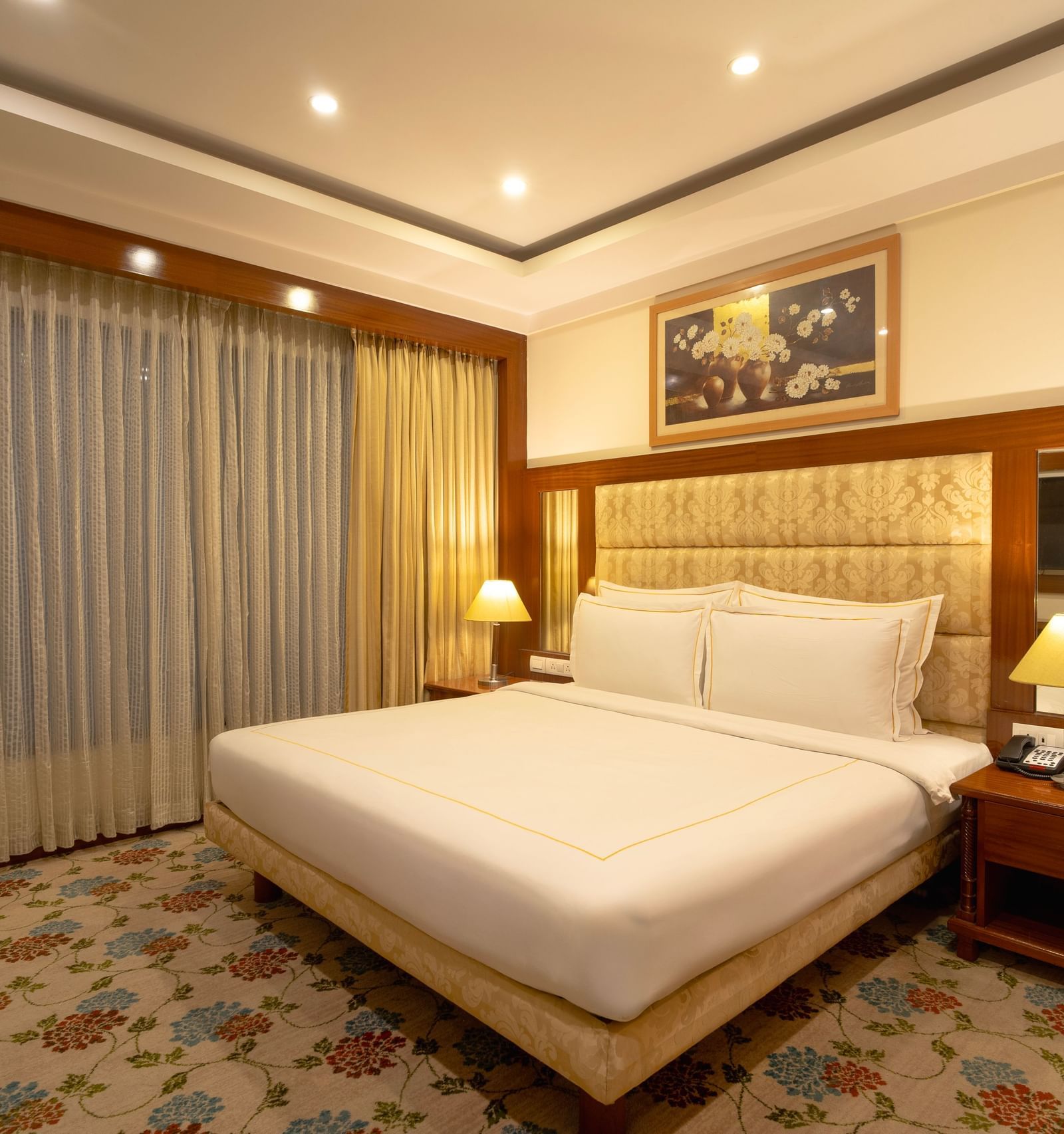 Accord Chrome hotel room featuring a king size bed, wooden headboard, nightstands, and warm lighting near a window.