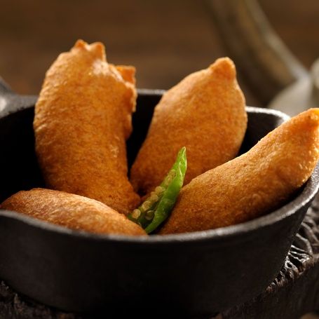 Deep-fried golden Banana Bajji in a cast iron pan.