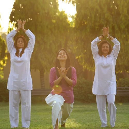 Group of women and a child participating in an outdoor wellness or meditation session on the lawn at Heritage Village Resorts & Spa, Manesar.
