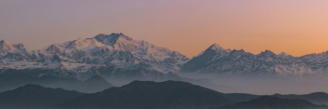 Mountain silhouette at dawn with layered hills in misty morning light creating dramatic Himalayan landscape