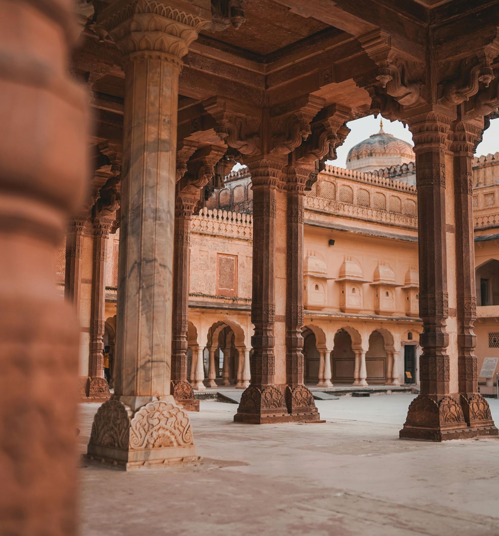 Ornate stone archways and columns frame a traditional Indian courtyard, hinting at historical architecture.