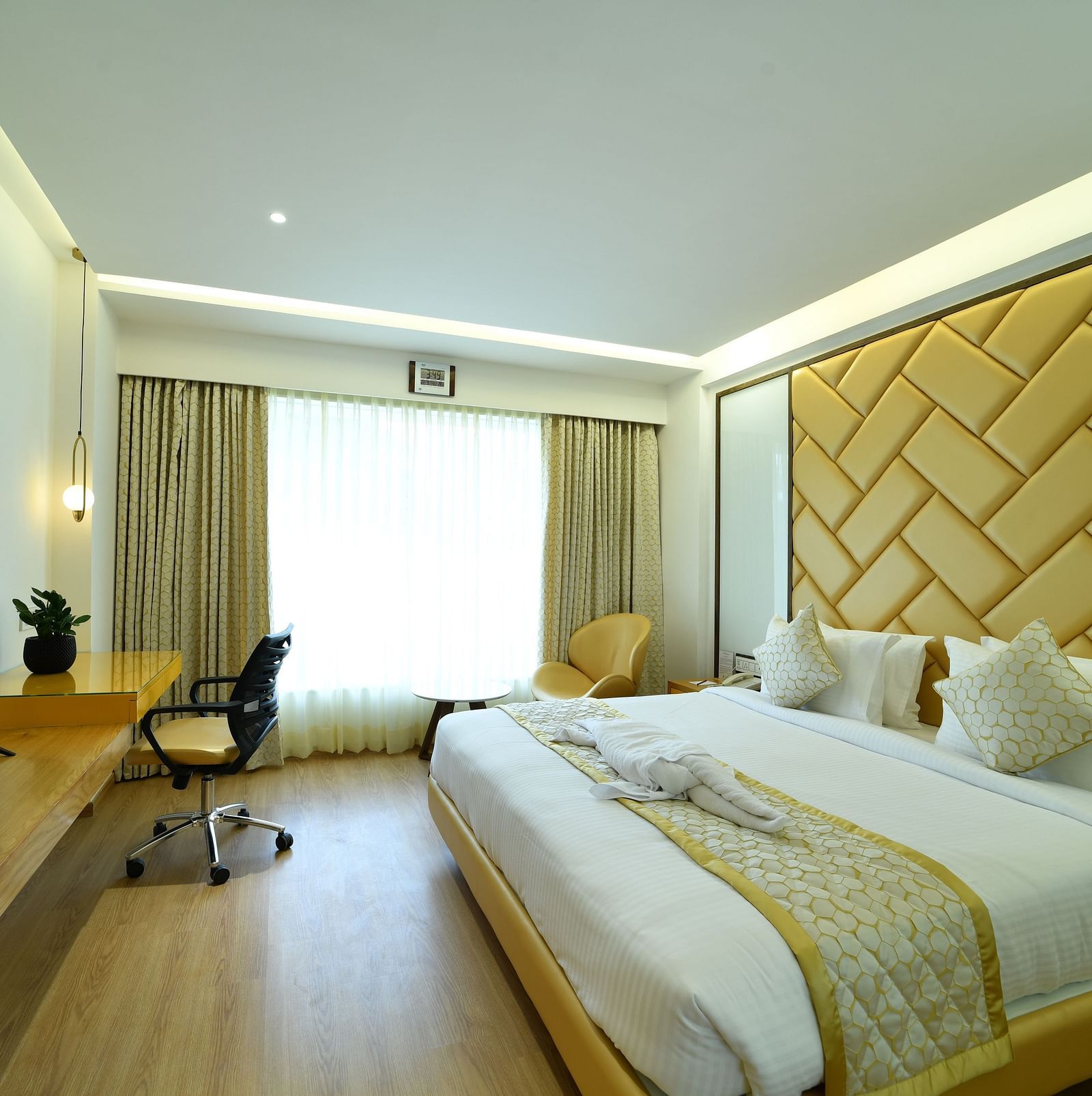 An image of a bedroom with a large bed and a workspace -The President Hotel, Kumara Park, Bangalore