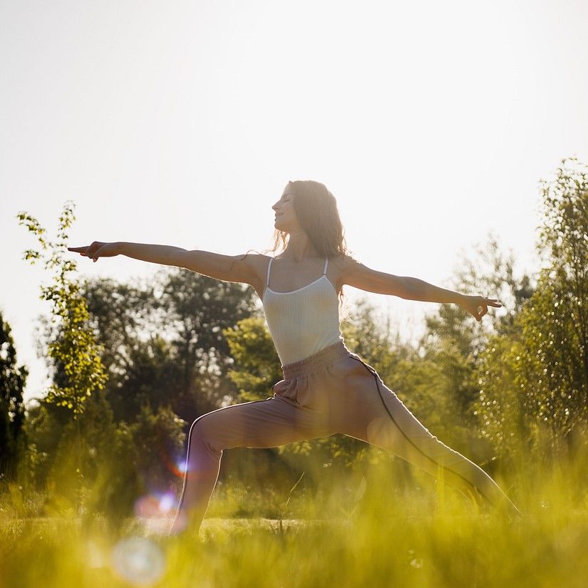 a woman doing a yoga pose during daytime while the sun shines