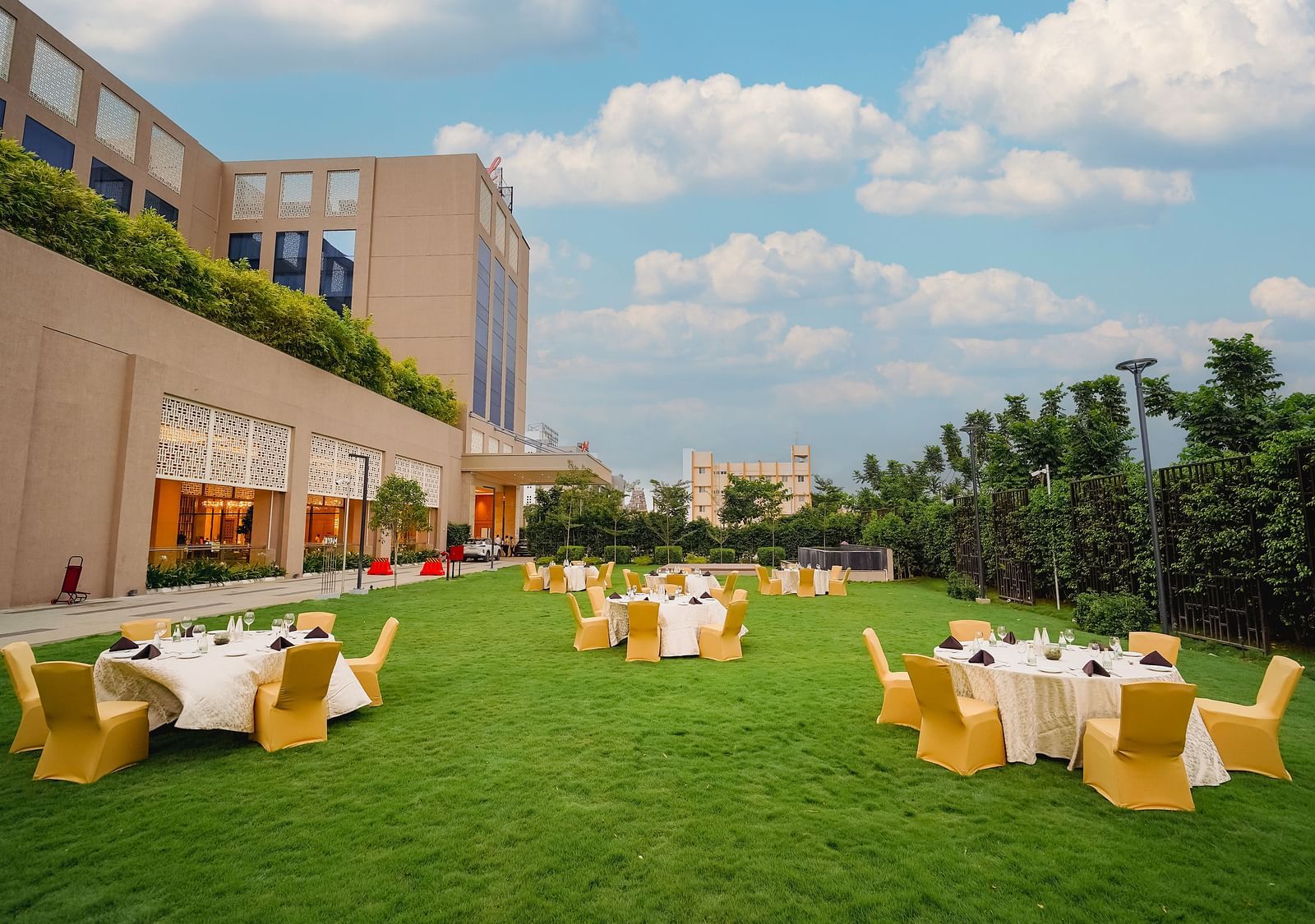 A beautifully manicured lawn with outdoor seating, perfect for events, surrounded by a hotel building