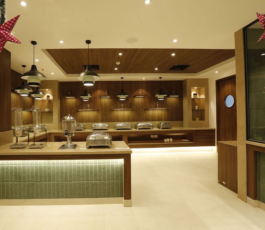 A poster of a buffet hall with several pots kept on the counter top table - Tulip Inn, Zirakpur