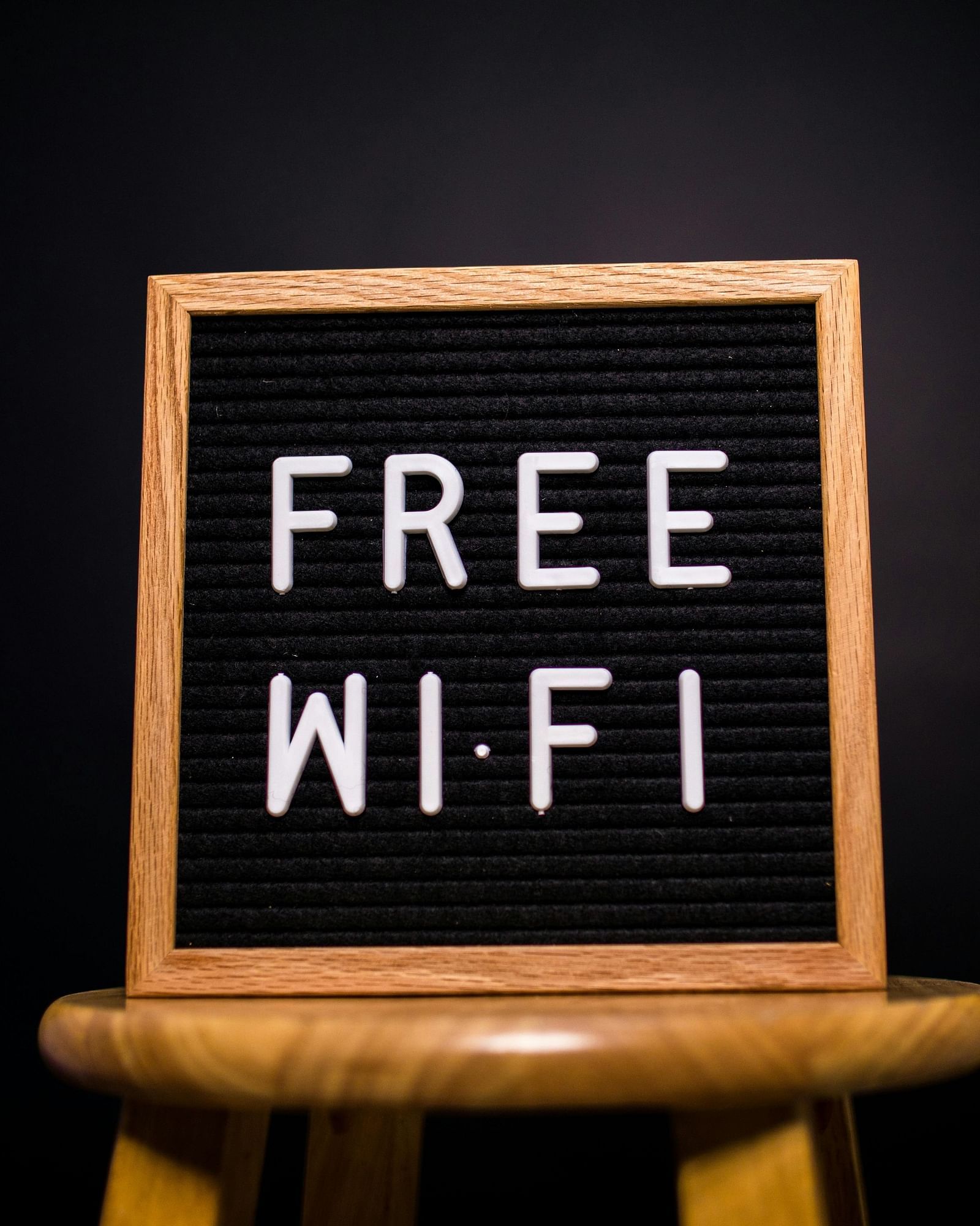 A small chalkboard sign on a wooden stand displaying FREE WI-FI in white letters against a black background.
