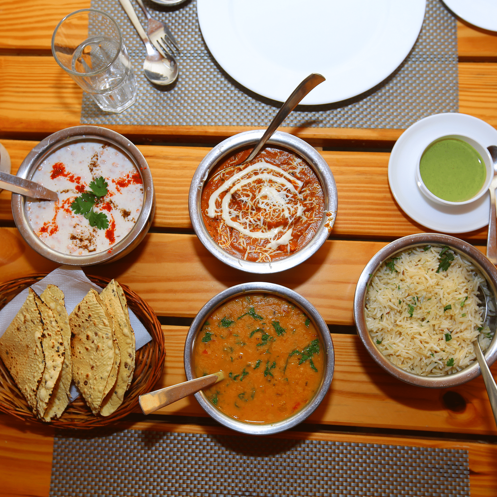 Image of Indian cuisine neatly arranged on the table with a tissue holder beside at Aanandam Resort & Spa