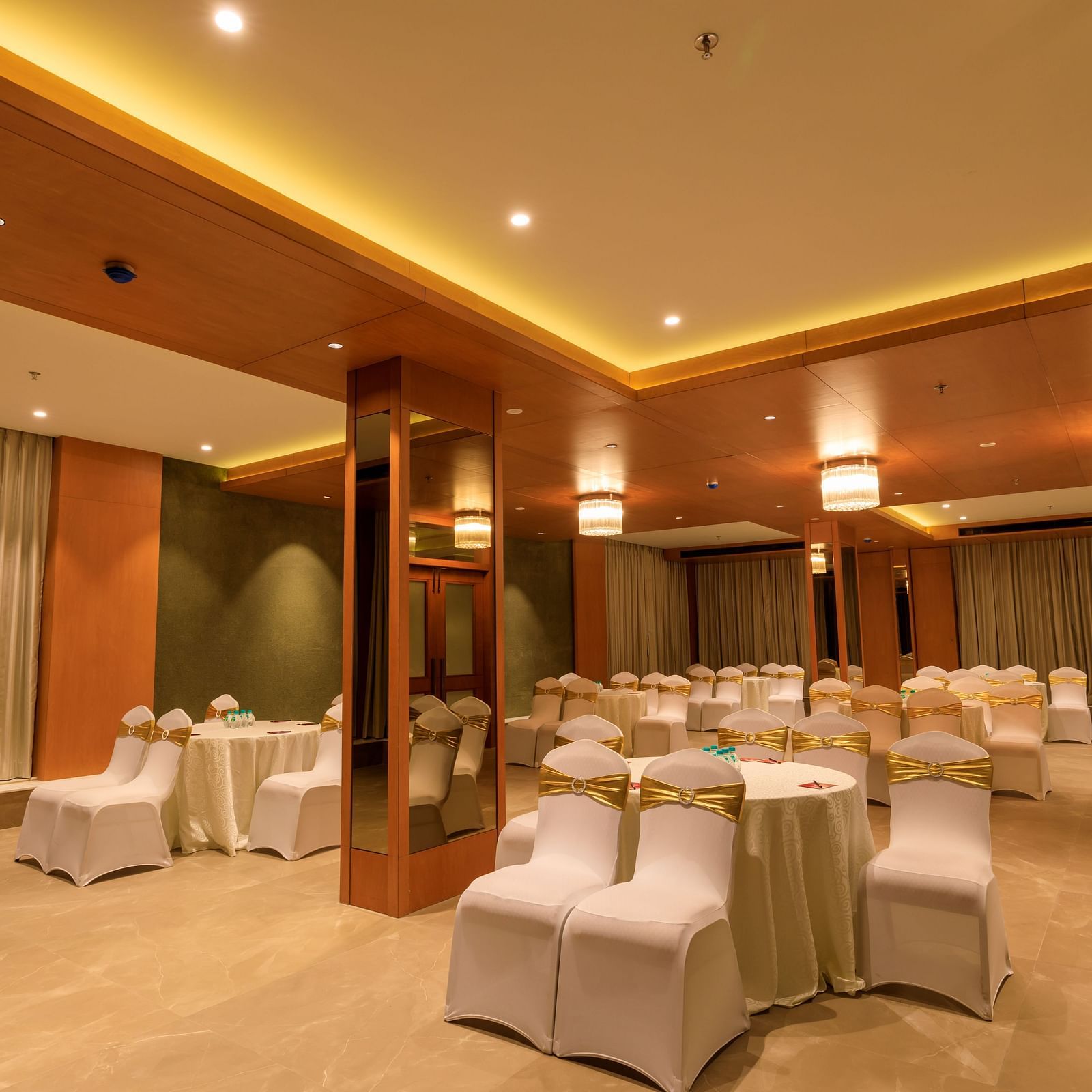A softly lit function room at Lords Eco Inn Apple Gate is arranged with round tables and covered chairs, ready for an event.
