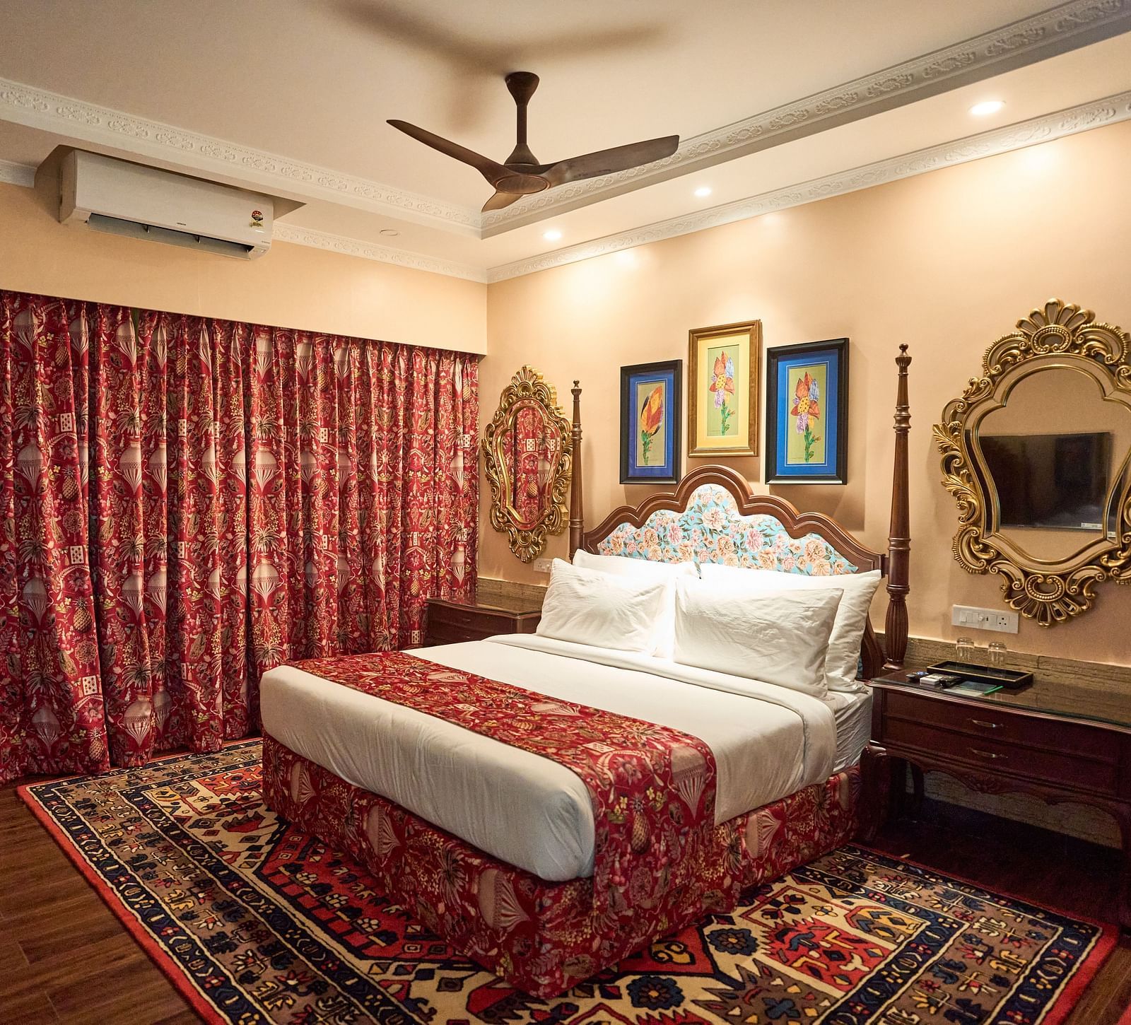 A spacious room featuring a large bed, wooden bedside tables, and windows draped with curtains at Mayfair Manor, Alibag