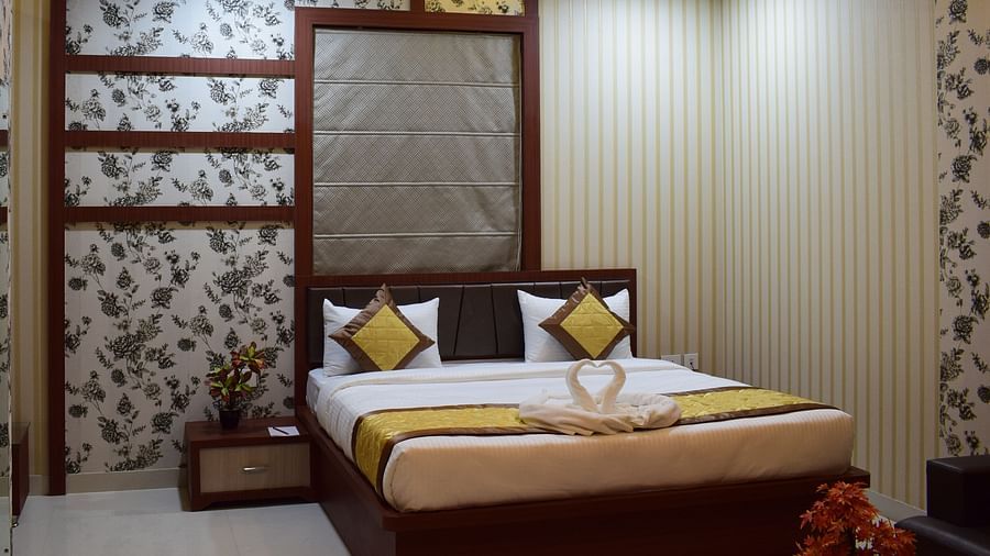 A spacious room featuring a large bed and a lit ceiling at Hotel Uday Palace