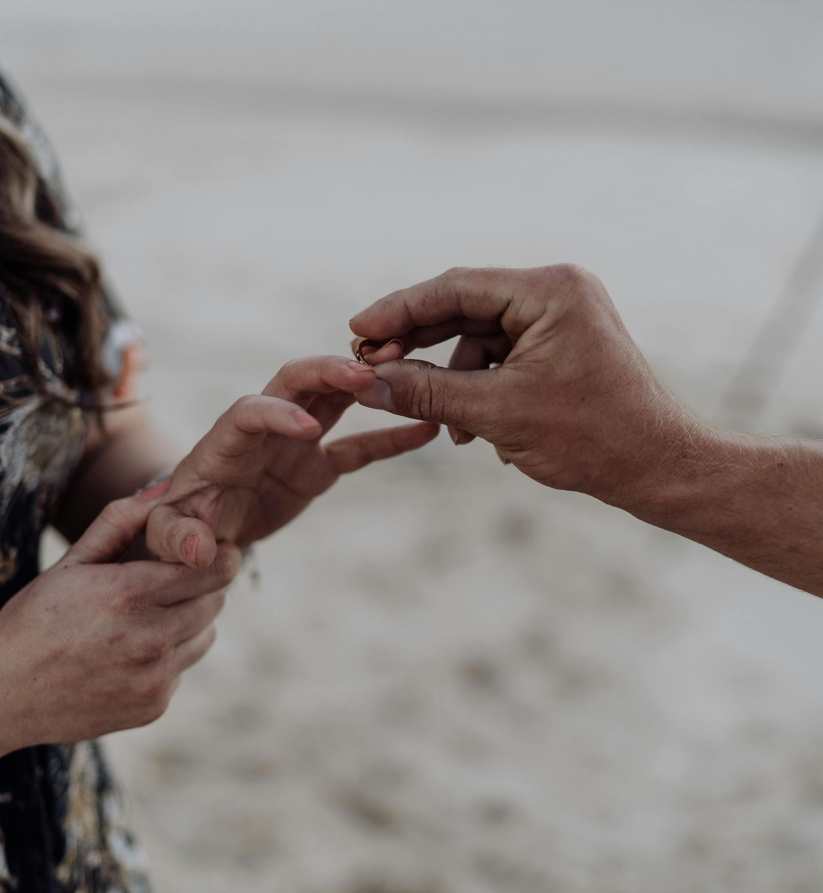 A close-up of a couple exchanging engagement rings on a beach.  | Mango Hill, Yercaud