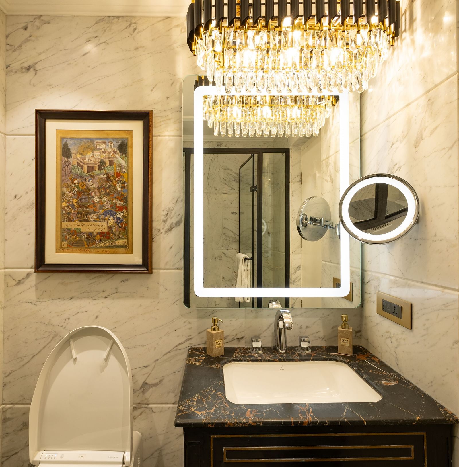 Washroom of Luxury King Bed Room with Balcony at The Claridges New Delhi, featuring a sleek sink, wall-mounted mirror, and an elegant chandelier hanging overhead