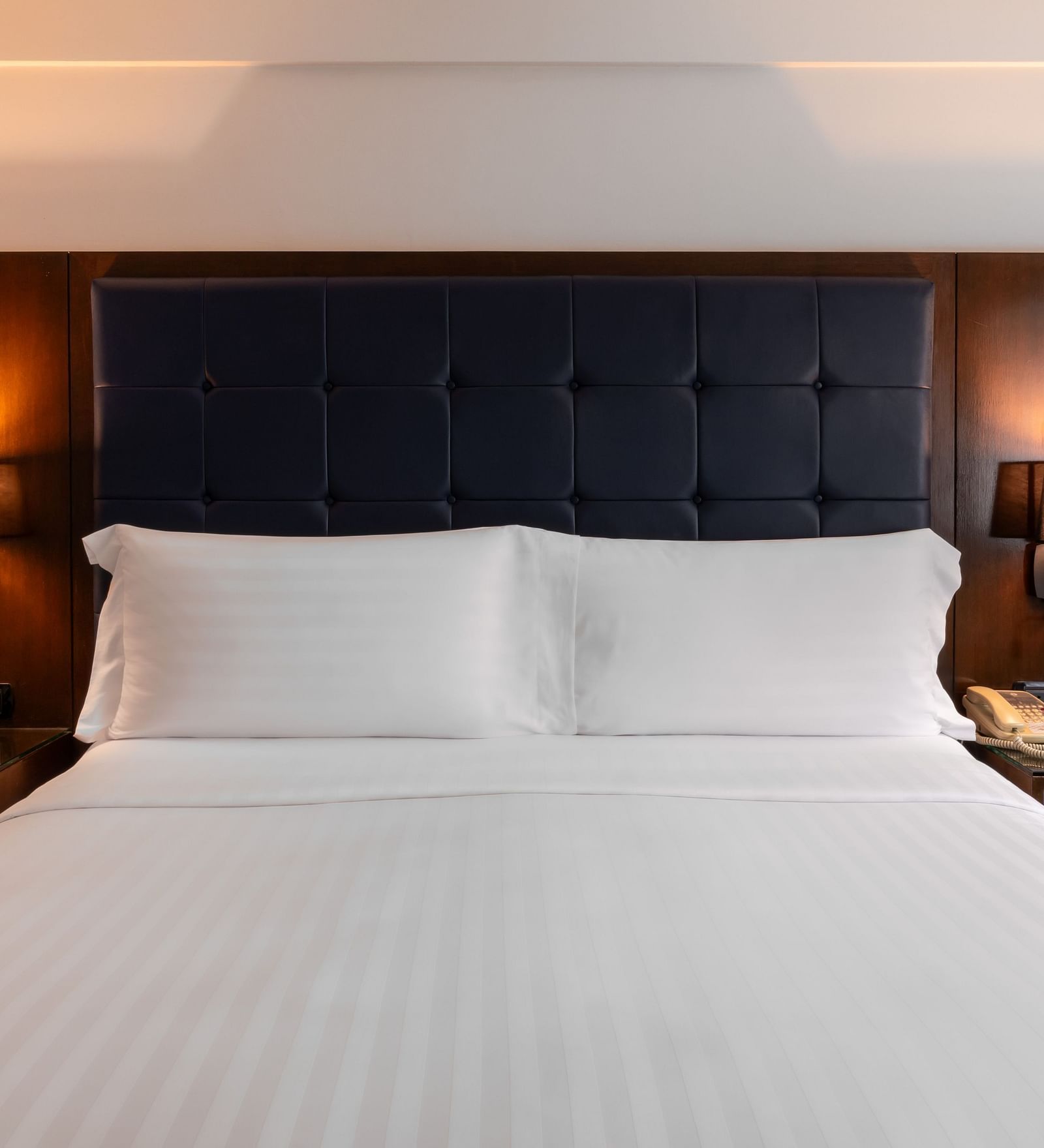 A close up shot of a king bed with side tables and lamps - Night Hotel Bangkok.
