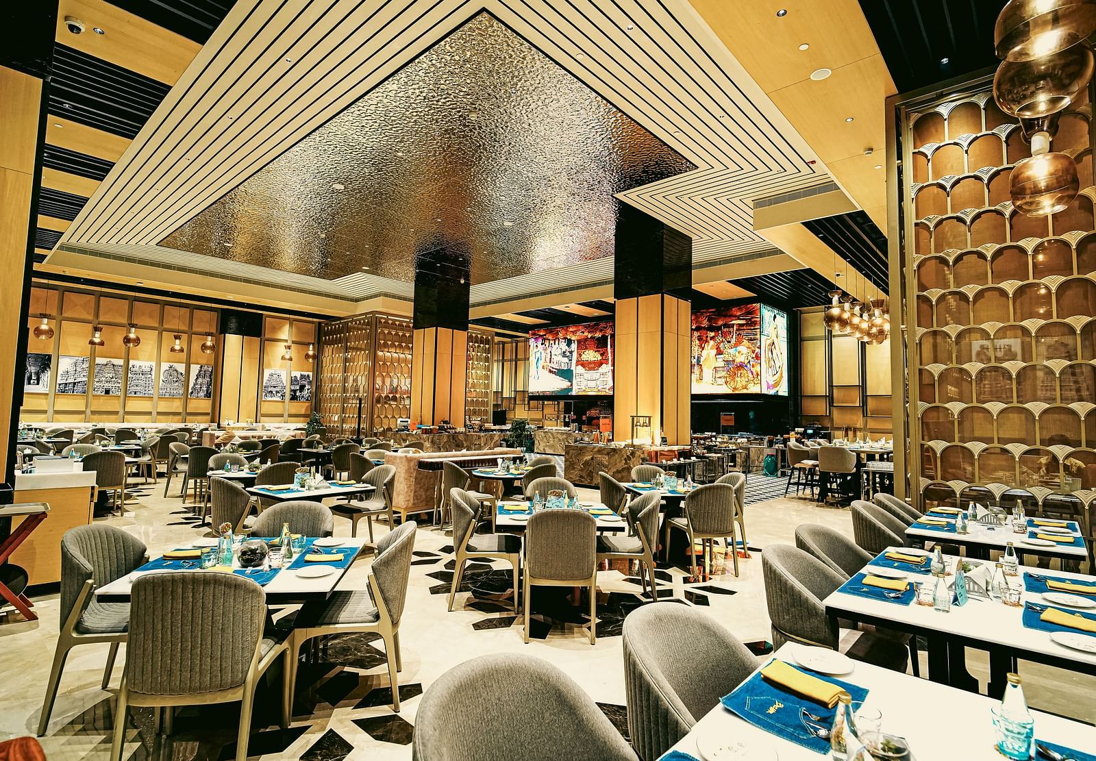 A wide view of the vibrant restaurant interior with elegant dining tables and unique ceiling design