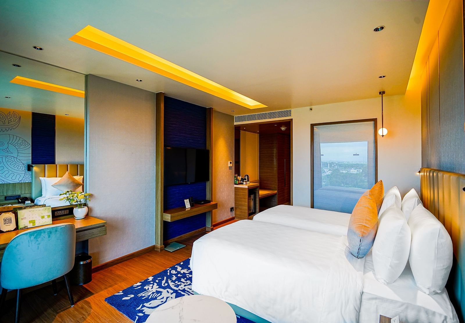 An image of Grand Club Temple View Room in Madurai with a twin bed, a work desk and hanging ceiling lamps