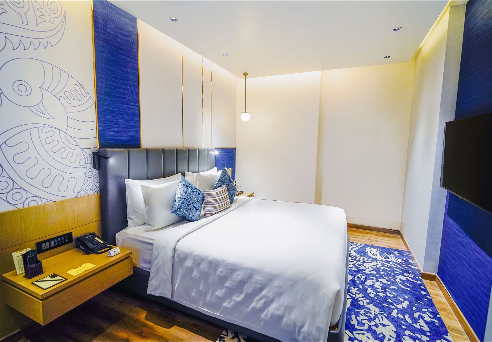 An image of our Junior Suite in Madurai with a night stand placed beside a plush bed