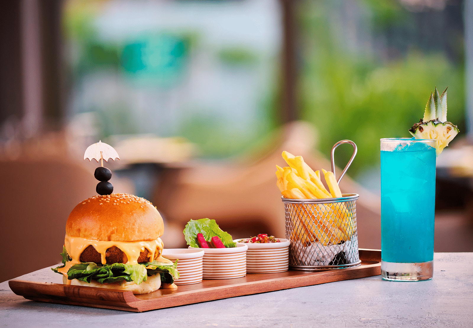 A meal of french fries and burger placed next to a blue drink.