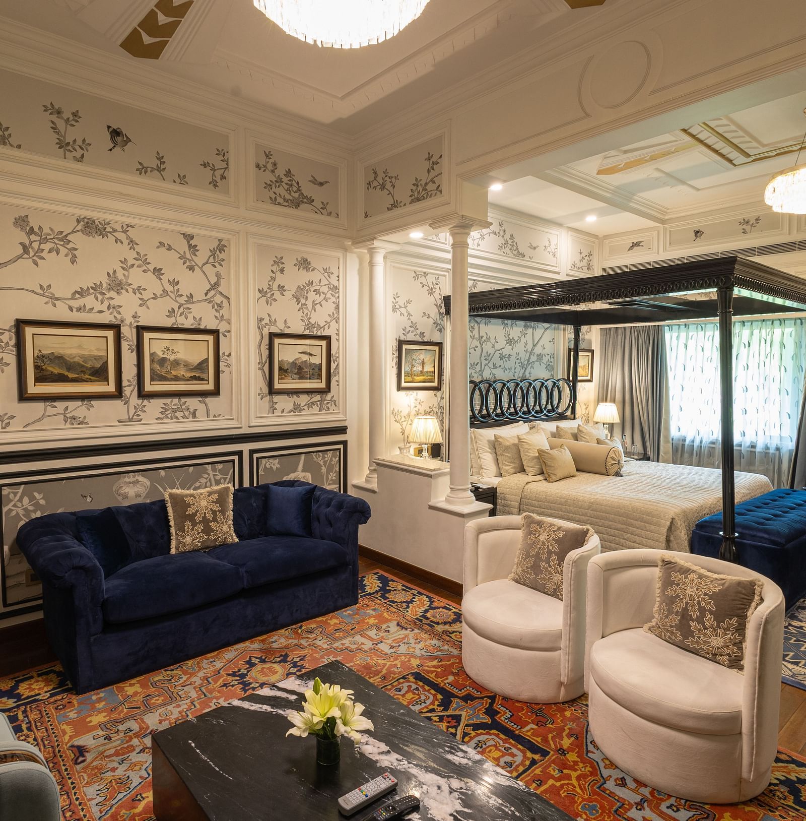 Grand Luxury Room at The Claridges New Delhi, featuring a cosy corner with a plush sofa and a chandelier hanging overhead