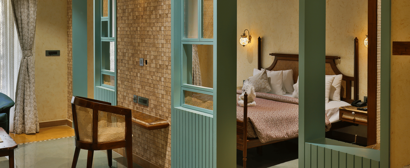 A view looking through a decorative teal wooden partition into a cosy, well-appointed bedroom - Tathastu Chavri Resort, Jawai