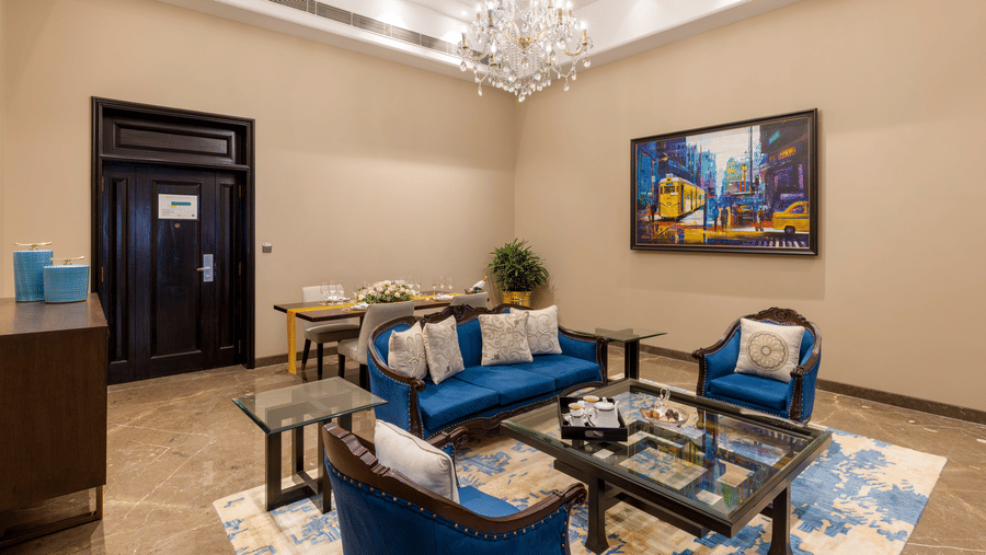 Presidential Suite lounge area with blue sofas and a chandelier at Kenilworth Hotel, Kolkata.
