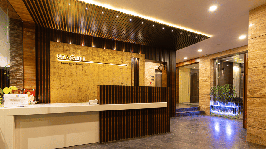 A reception area with front desk, seating space, ceiling lights, and wall decor at Hotel Seagull Digha.