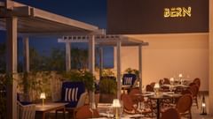 A hotel rooftop restaurant at Sarovar Portico, Hanumangarh, with tables, chairs, and lamps.