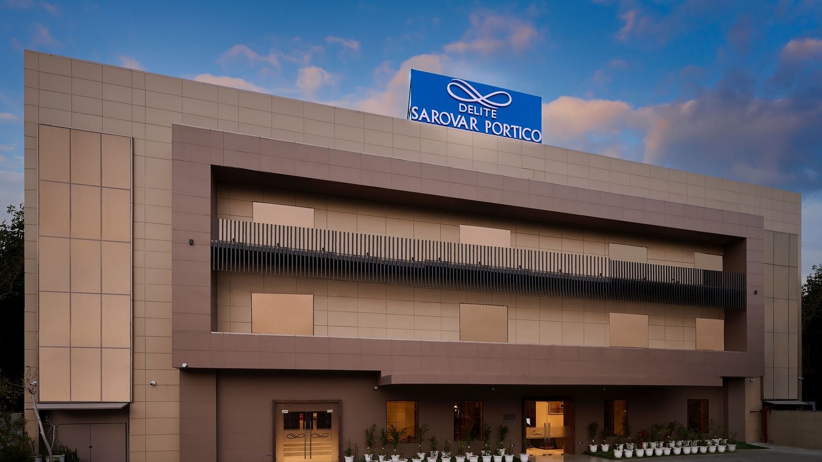 A facade image of a hotel with a sign board of the hotel name on the top