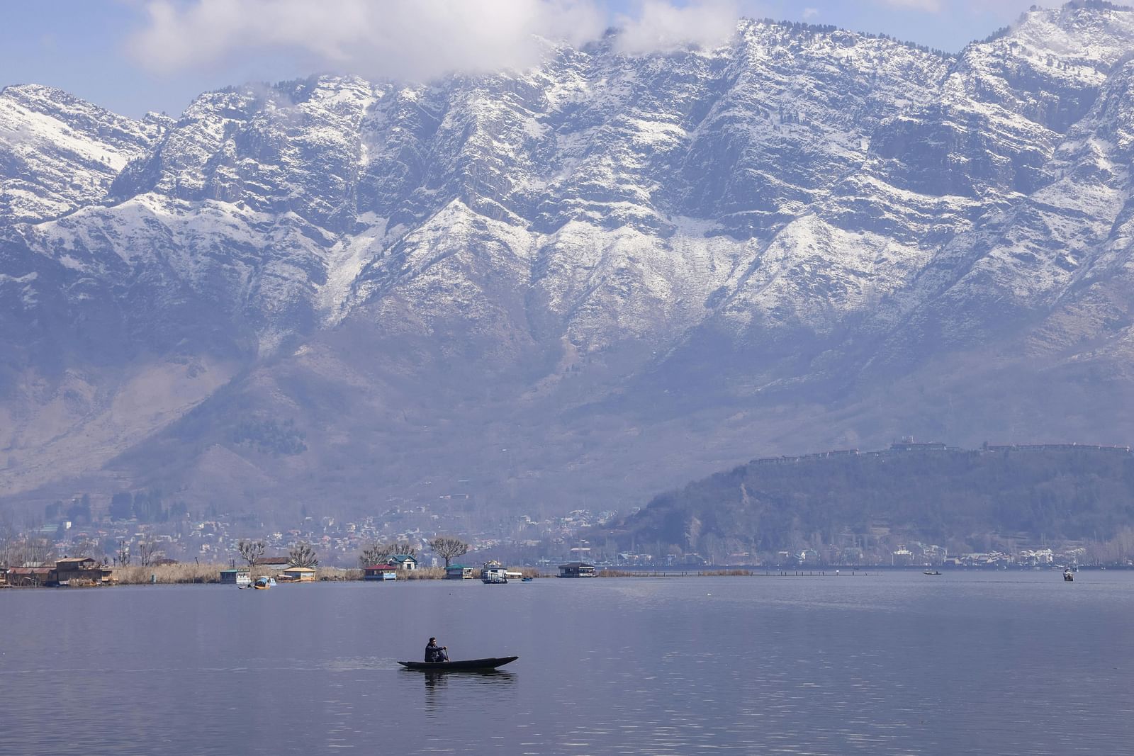 Shikara on Dal Lake with snow-capped mountains in the background.