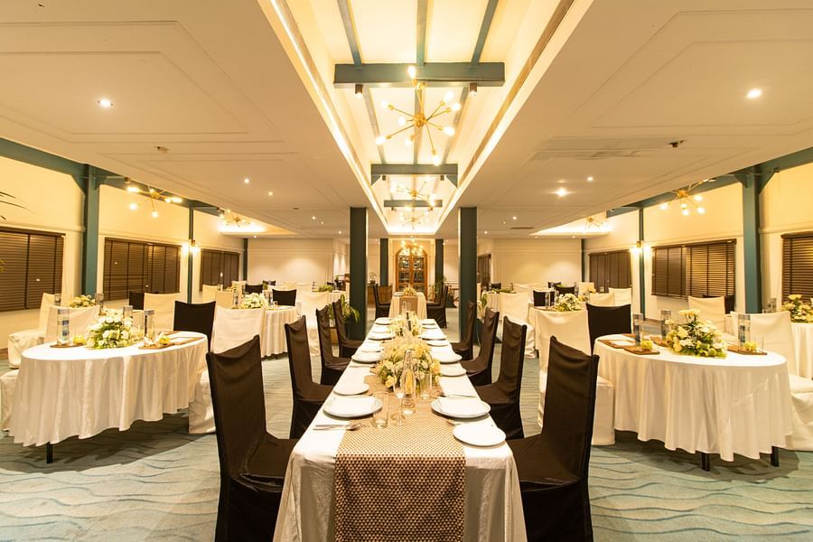 Spacious banquet hall with a modern chandelier, tables arranged for an event, and a cozy, inviting atmosphere.
