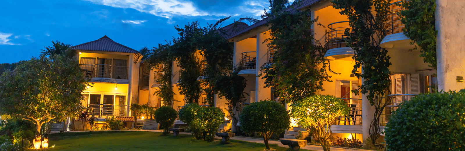Two-storey hotel complex illuminated at dusk with ivy-covered walls and a green lawn - Hotel Seagull Digha