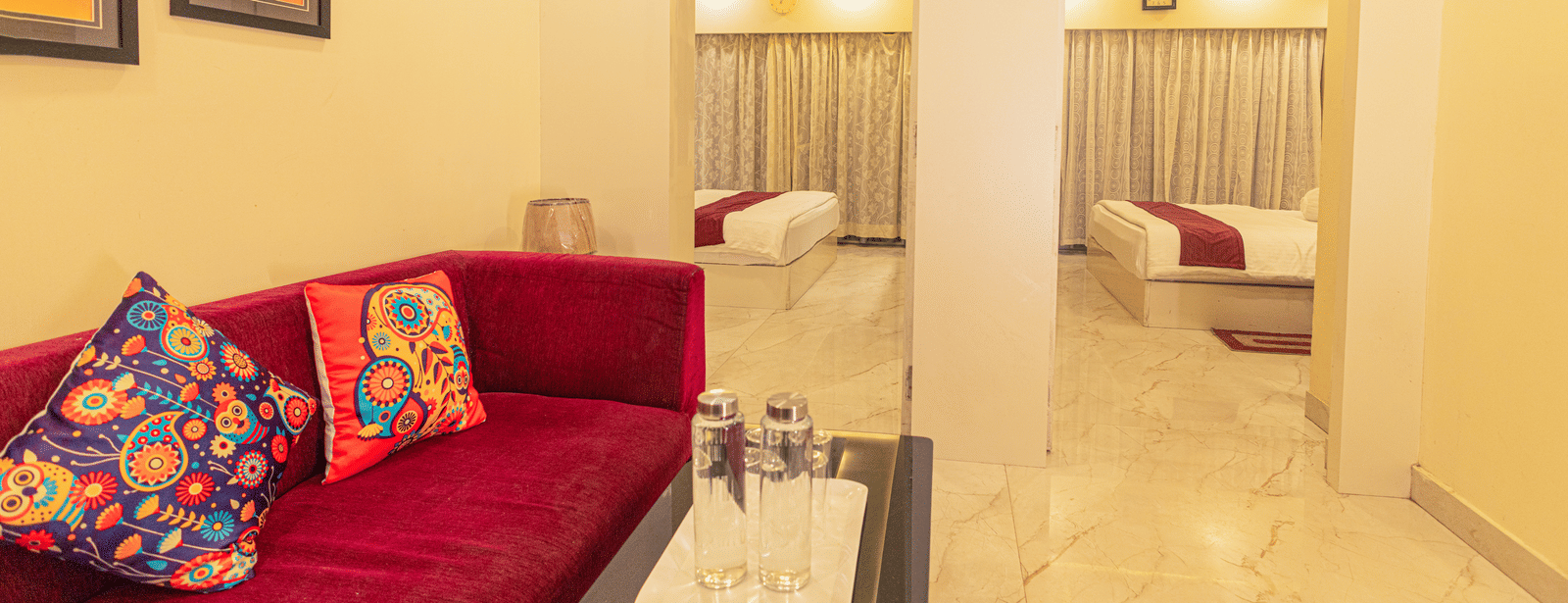 A suite at Hotel Seagull Digha featuring a living area with a sofa and table, and 2 beds in separate rooms visible through open doorways.