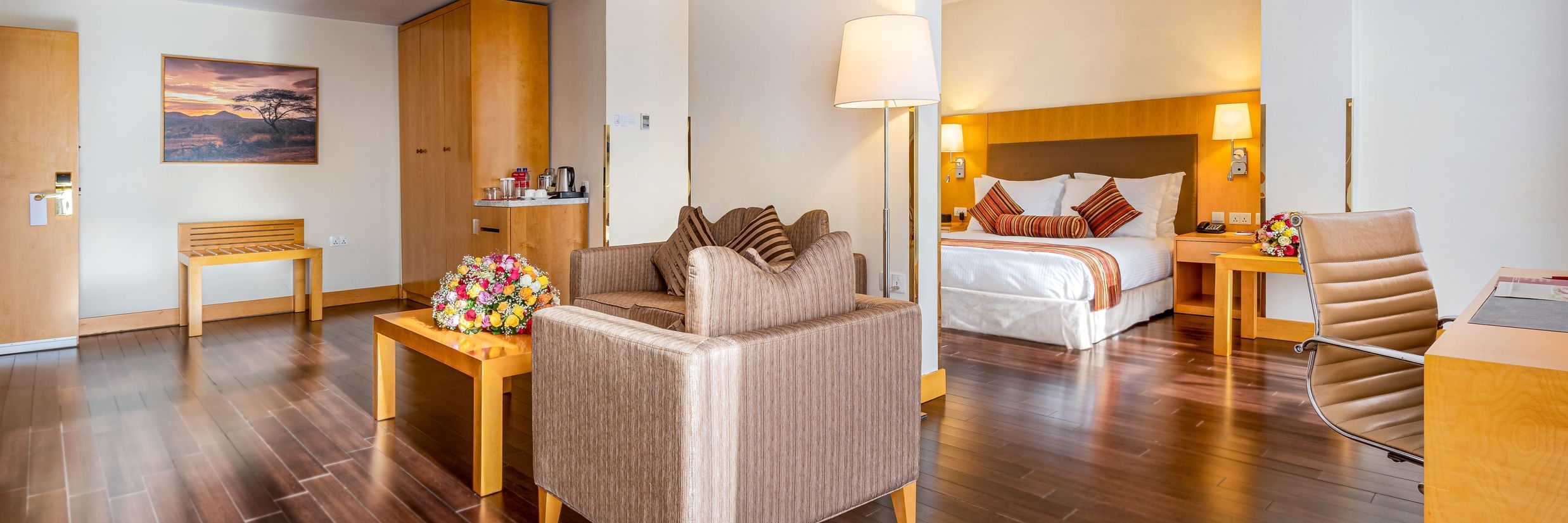 a suite with the bedroom and the living room, with wardrobes, sofa chairs, teapoy, and wall decors in view at Ramada by Wyndham Addis, Addis Ababa
