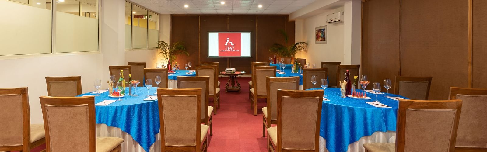 Image of Senate Conference Hall with cluster seating arrangement, blue tables and chairs  | Inde Hotel Cyber City