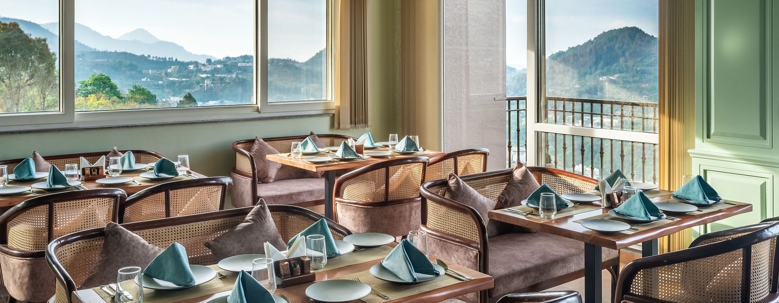 an image of a dining space filled with natural light, chairs and tables are placed with cutlery and hand towels at Mountoria Retreat, Naukuchiatal