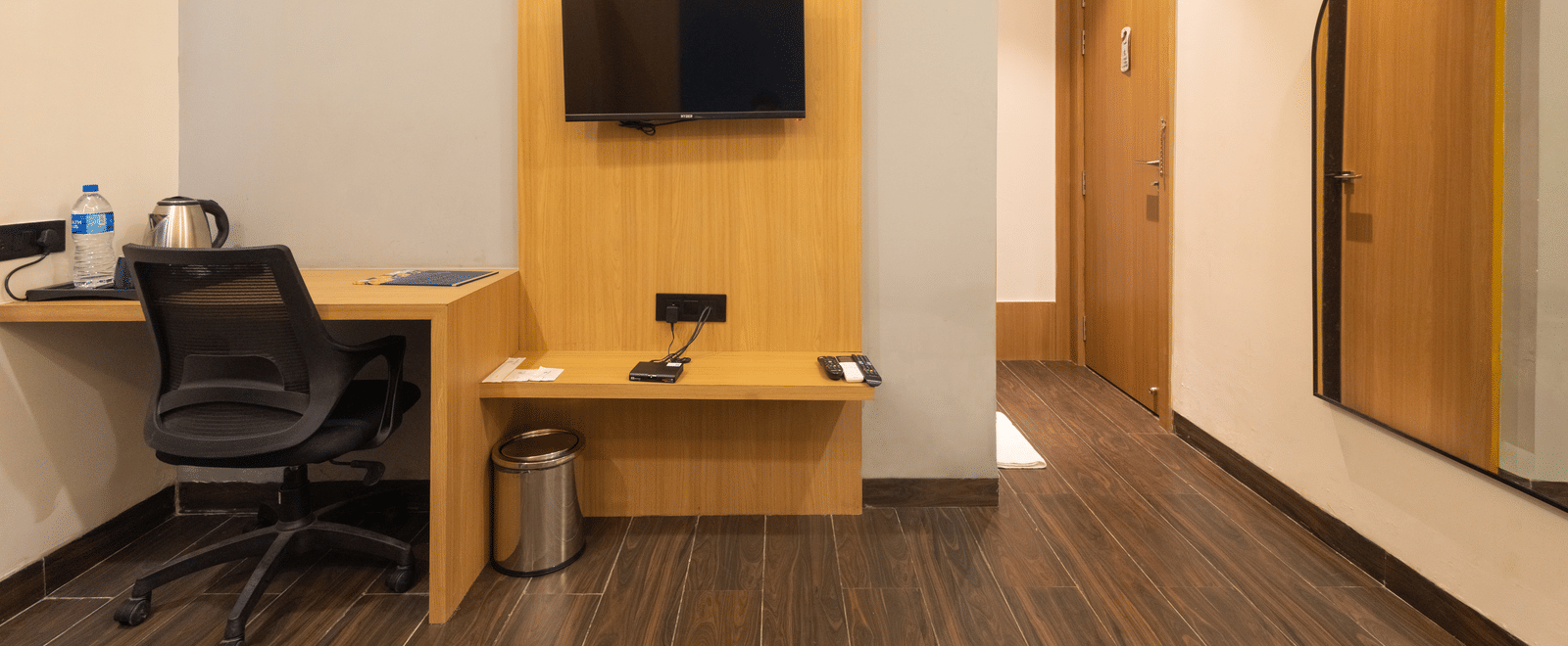 Interior view of a guest room showing the television, desk, and doorway at Pravasa Stay Luv Kush, Indore.