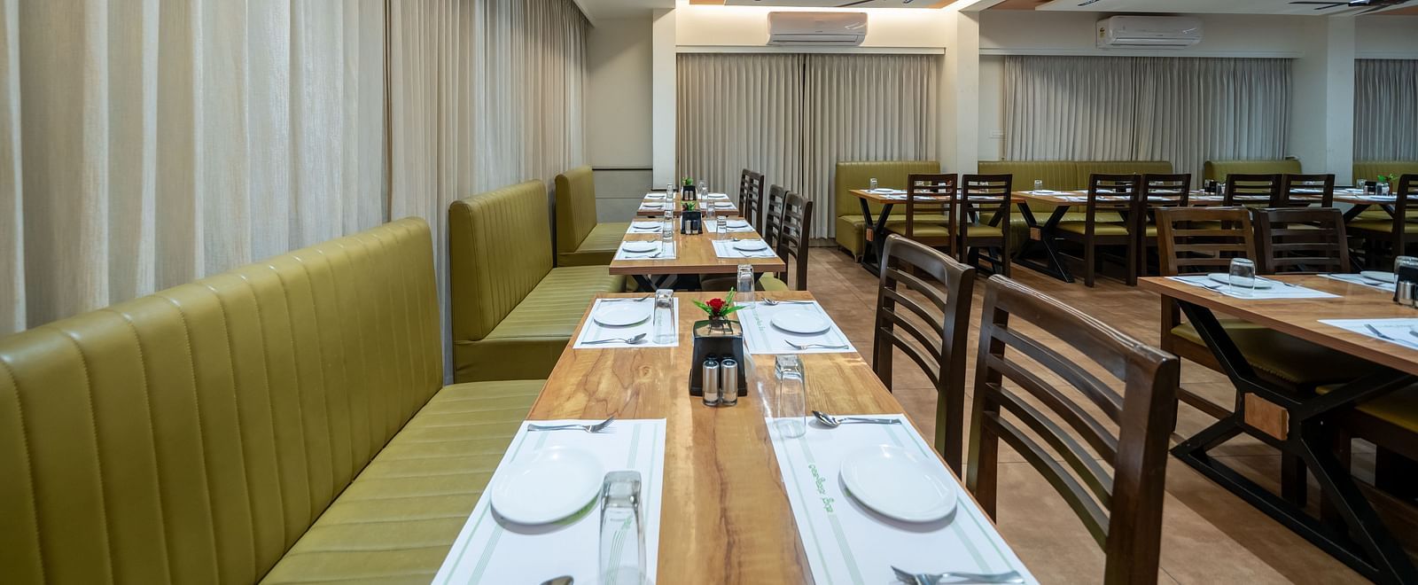 Close-up view of a fully set table at Hari Govinda's, with a chair on one side and cushioned furniture on the other side for seating