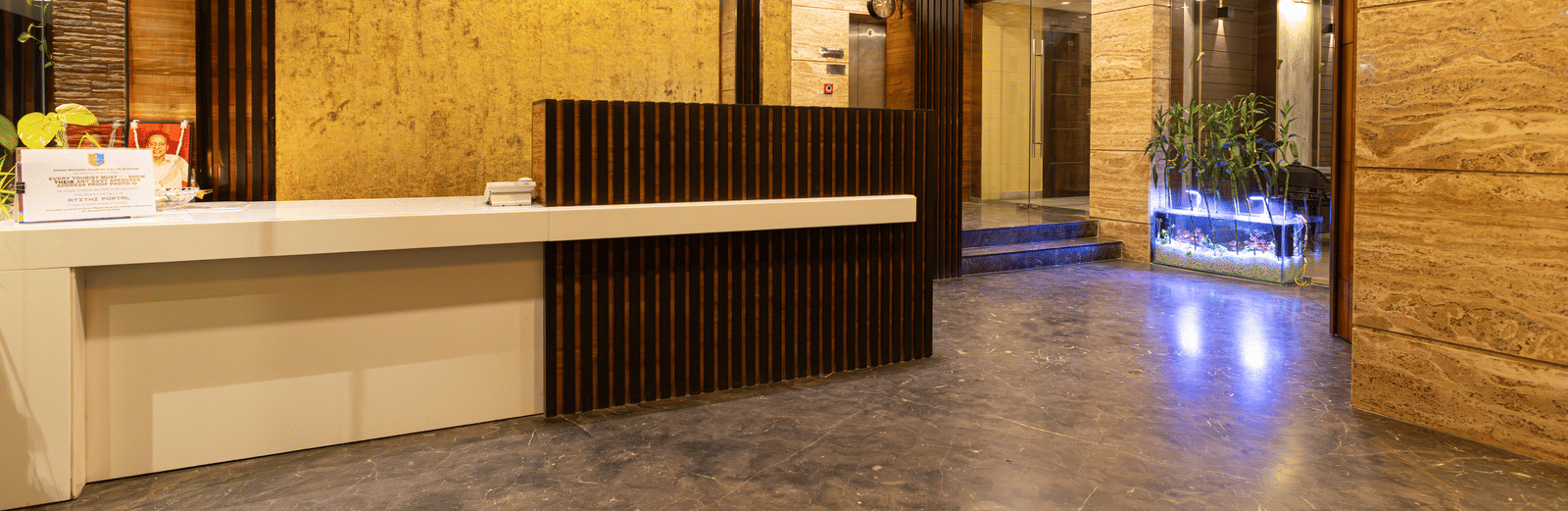 Spacious hotel lobby interior with a sleek wooden reception desk and warm lighting - Hotel Seagull Digha