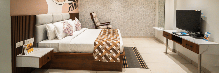 An image of a hotel bedroom with a large bed placed in front of a wall-mounted television - MGM Whispering Meadows