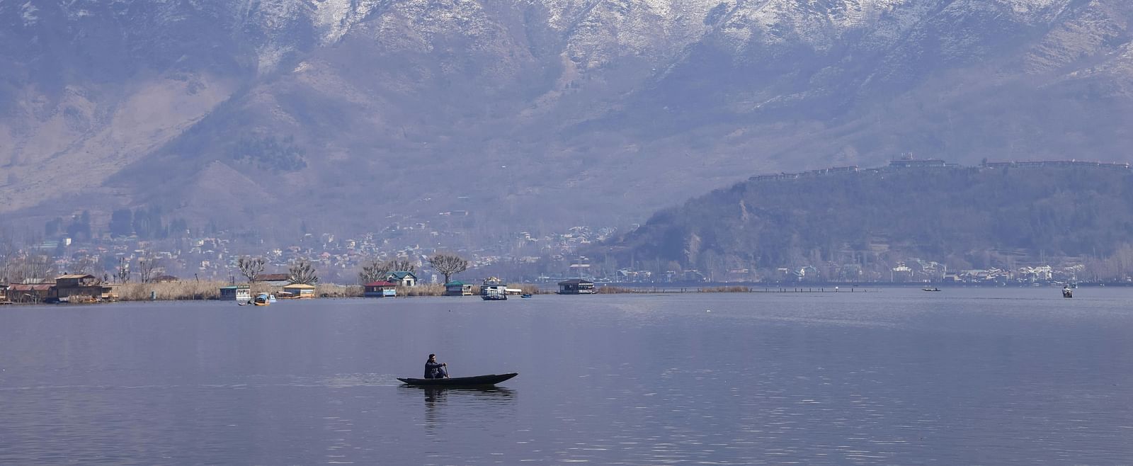 Shikara on Dal Lake with snow-capped mountains in the background.