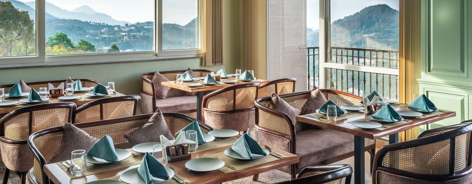 an image of a dining space filled with natural light, chairs and tables are placed with cutlery and hand towels at Mountoria Retreat, Naukuchiatal