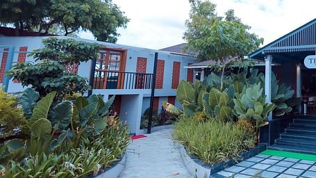 Garden entrance path with lush greenery leading to a villa at Trishvam Symphony, Krishnagiri.