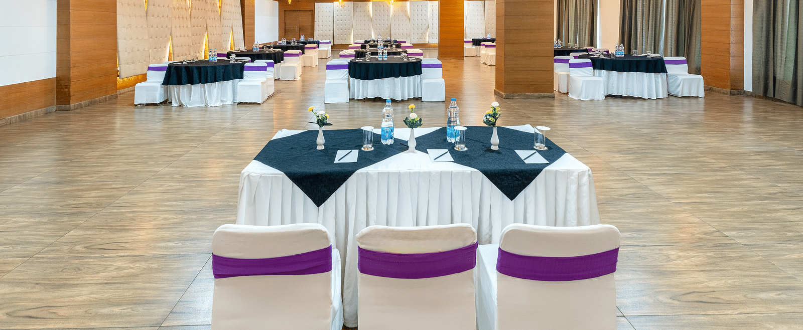 A larger empty event hall with white tables and chairs - Via Lakhela Resort & Spa